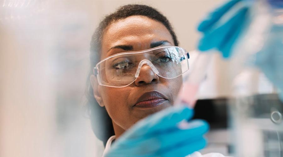 Scientist wearing safety glasses looking at test tube 